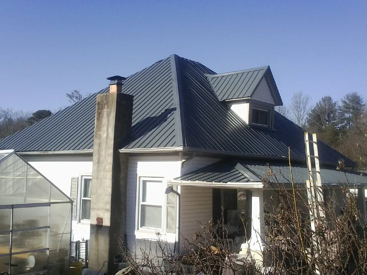 Dark blue standing seam metal roof on a white farmhouse with dormer — Slate & Tile Roof Repair by Roofing Brothers in Arona