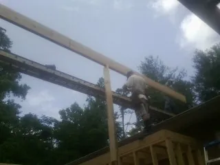 Carpenter setting a ridge beam over a new addition frame — Ice Dam Removal by Roofing Brothers in Arona