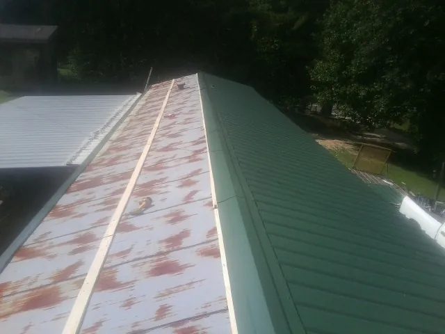 Old rusted panels beside newly installed green metal roofing — Wind Damage Roof Repair by Roofing Brothers in Arona