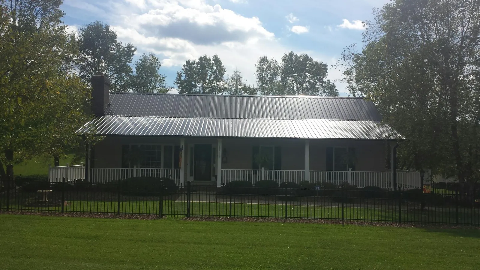 Gray metal roof on a brick ranch with a full width front porch — Gutter Guard Installation work by our crew in Arona