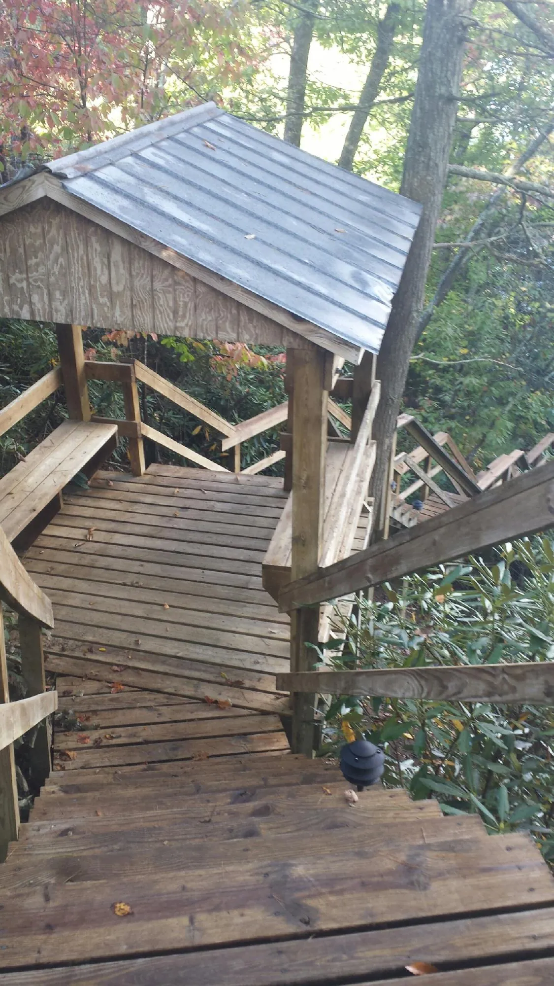 Metal roofed shelter over wooden steps on a wooded walkway — Skylight Repair & Installation work by our crew in Arona