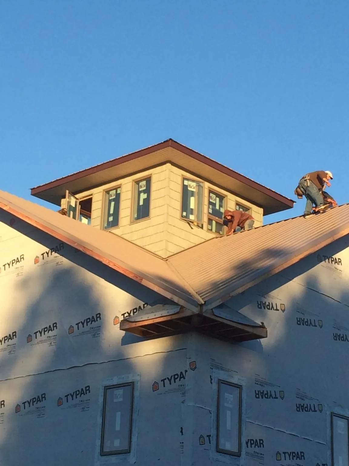 Roofers working around a rooftop cupola on a new metal roof at sunset — Roof Waterproofing in Arona by Roofing Brothers